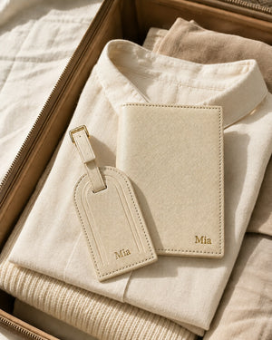 Ivory personalised passport cover and matching luggage tag resting on folded clothing inside an open suitcase