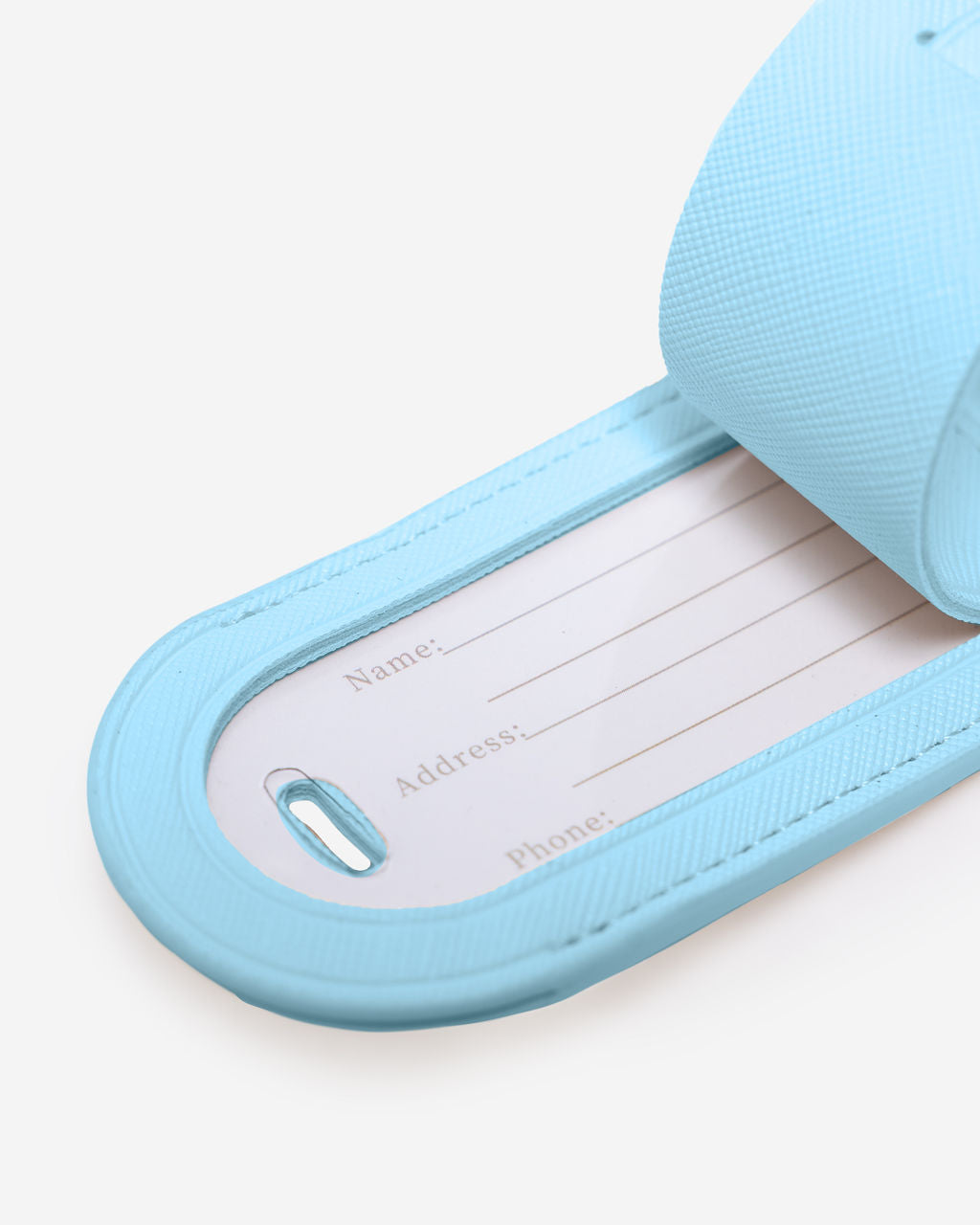 Close-up of a light blue Saffiano leather luggage tag with the internal white card showing fields for Name, Address, and Phone.