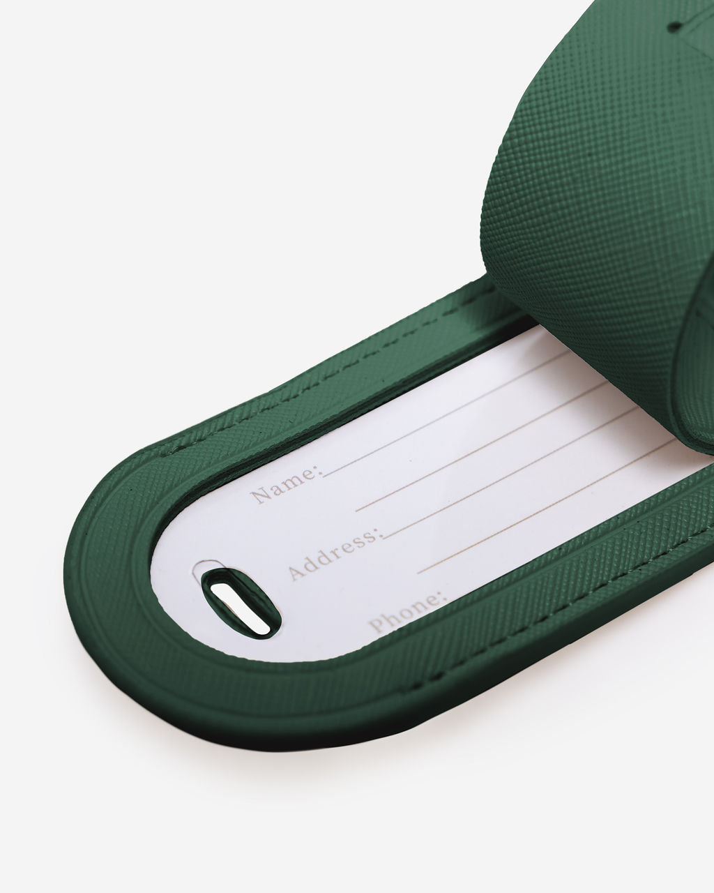 Close-up of a green Saffiano leather luggage tag showing contact info fields for name, address, and phone number.