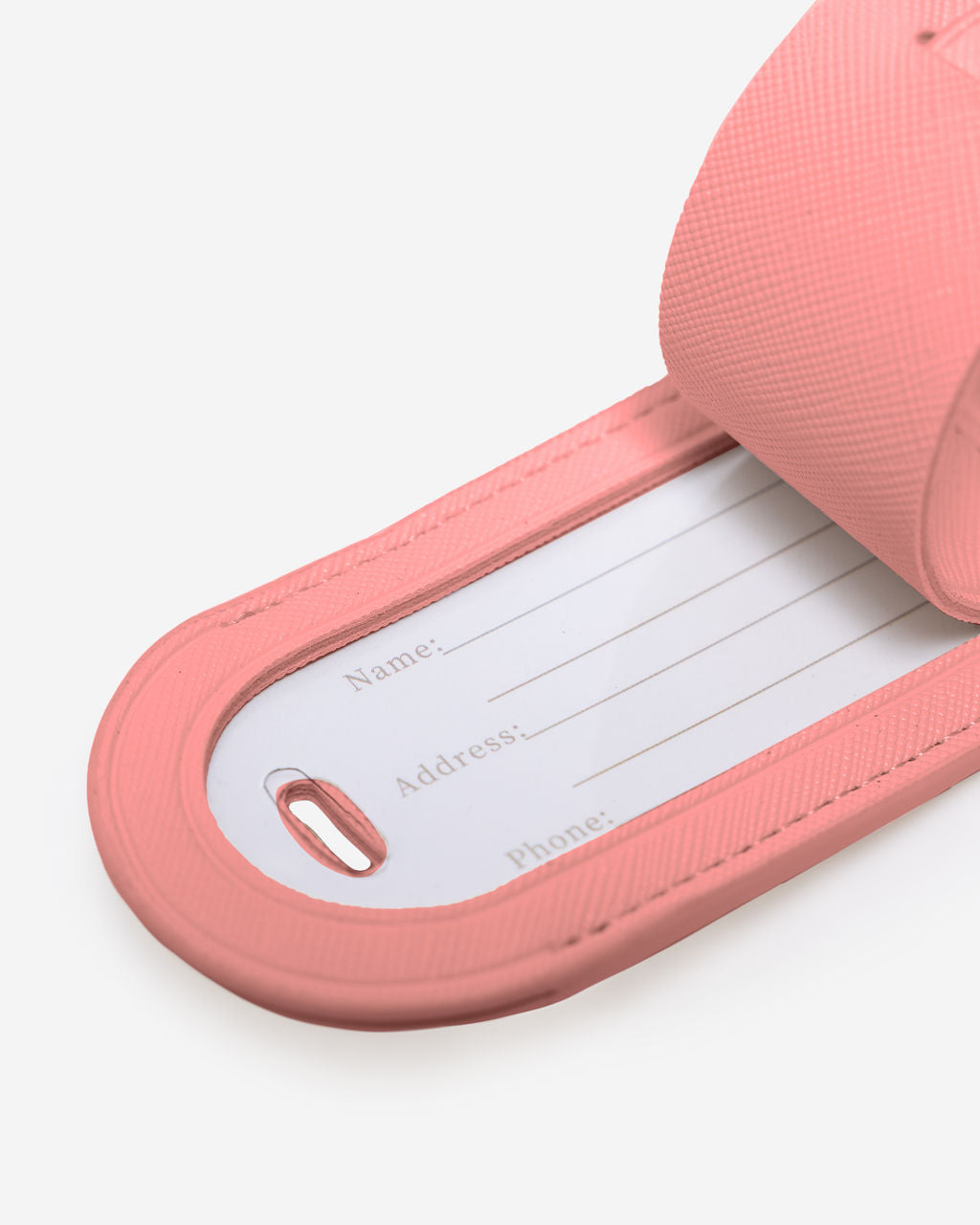 Close-up of a light pink Saffiano leather luggage tag with the internal white card showing fields for Name, Address, and Phone.