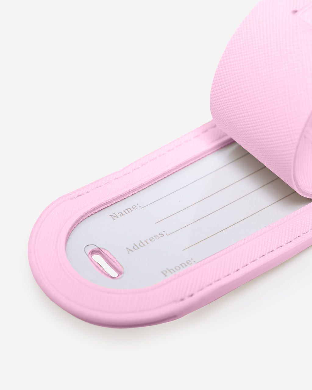 Close-up of a light pink Saffiano leather luggage tag showing contact info fields for name, address, and phone number.