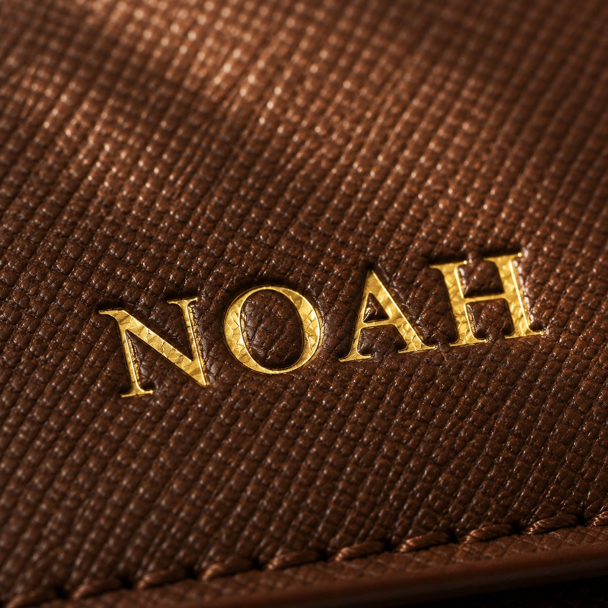 Brown leather surface with 'NOAH' embossed in gold.