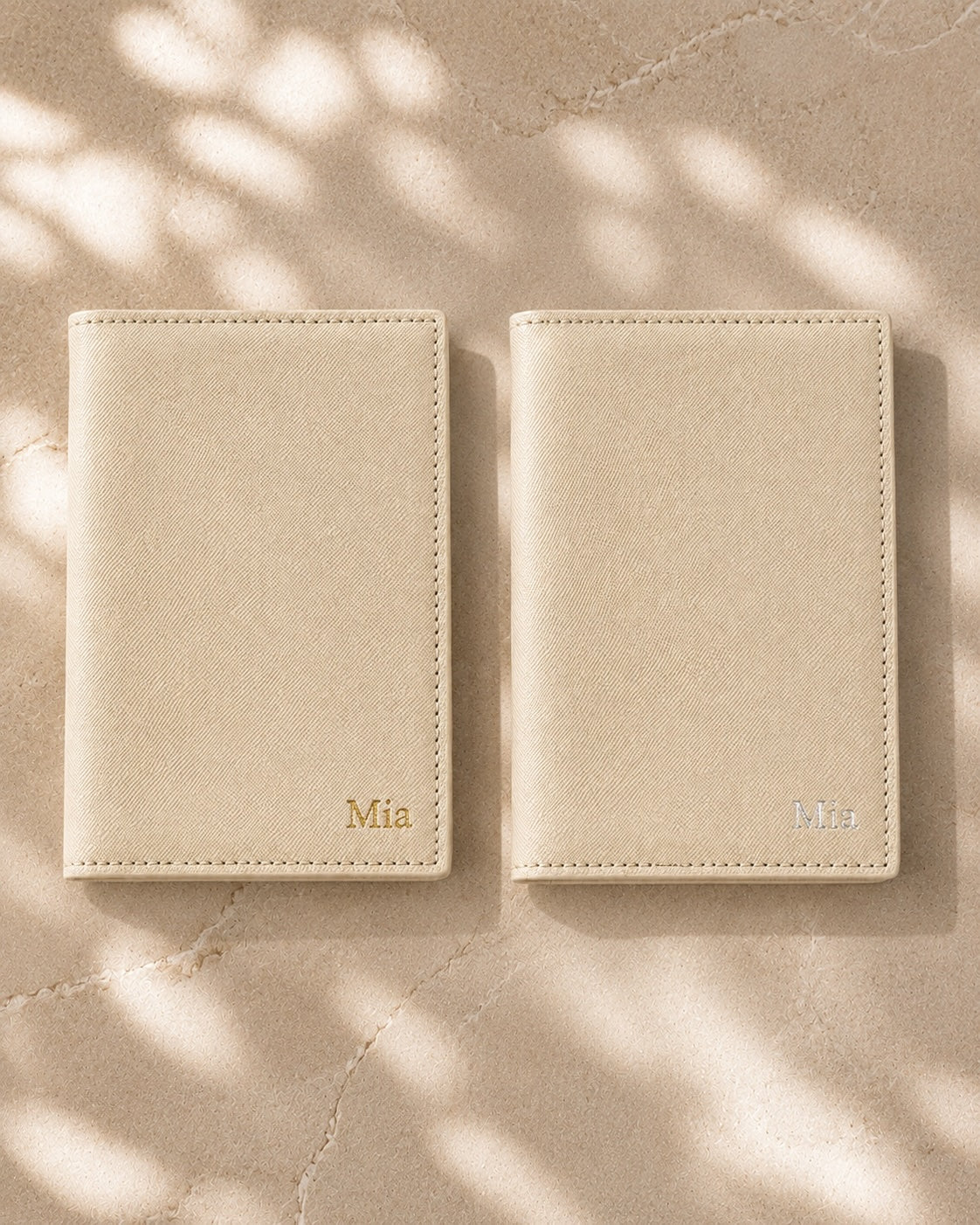 Two ivory personalised passport covers side by side, one with gold foil embossing and one with silver foil embossing