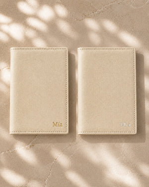 Two ivory personalised passport covers side by side, one with gold foil embossing and one with silver foil embossing