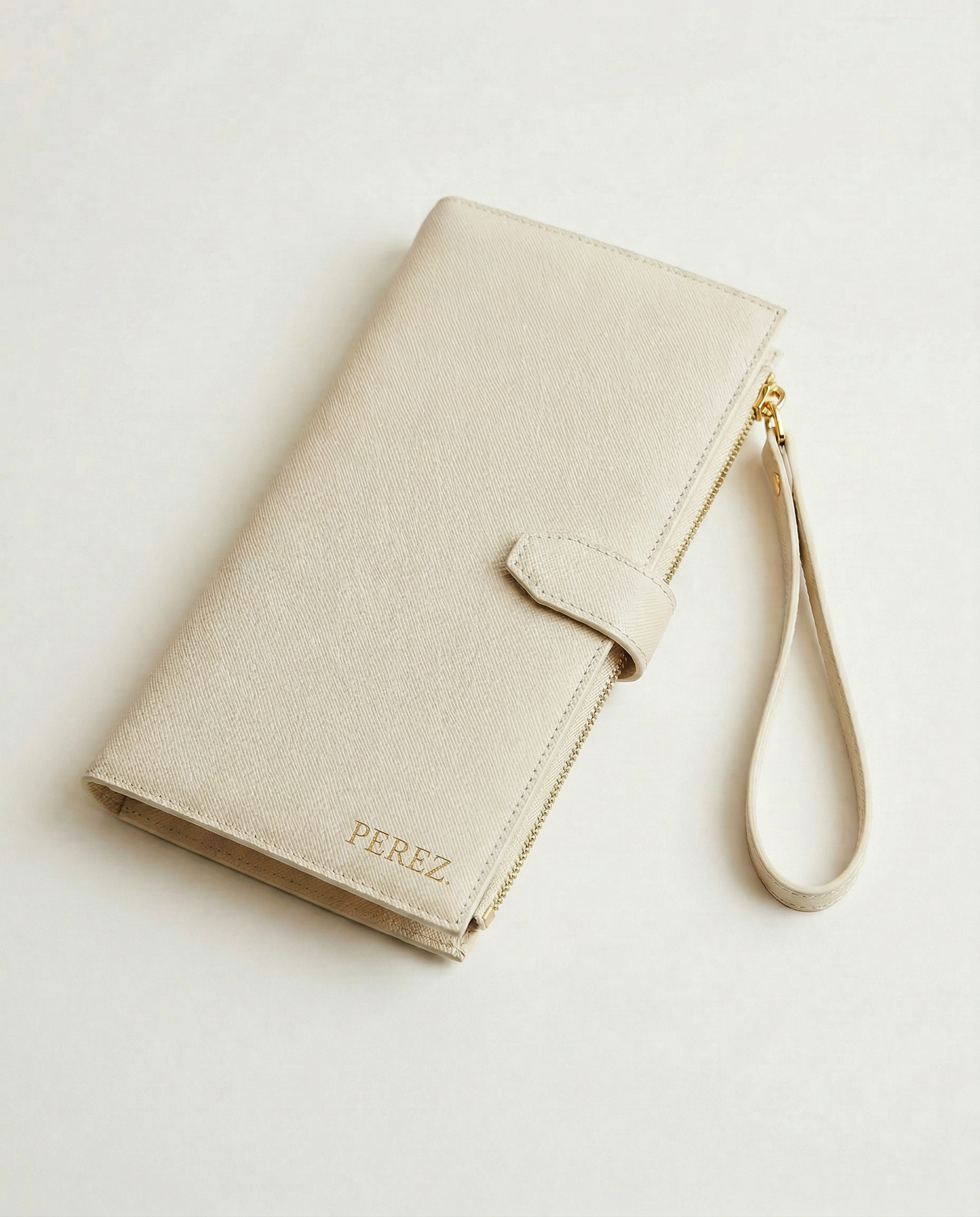Personalised Family travel wallet in beige with clasp and wrist strap, featuring embossed name detail.