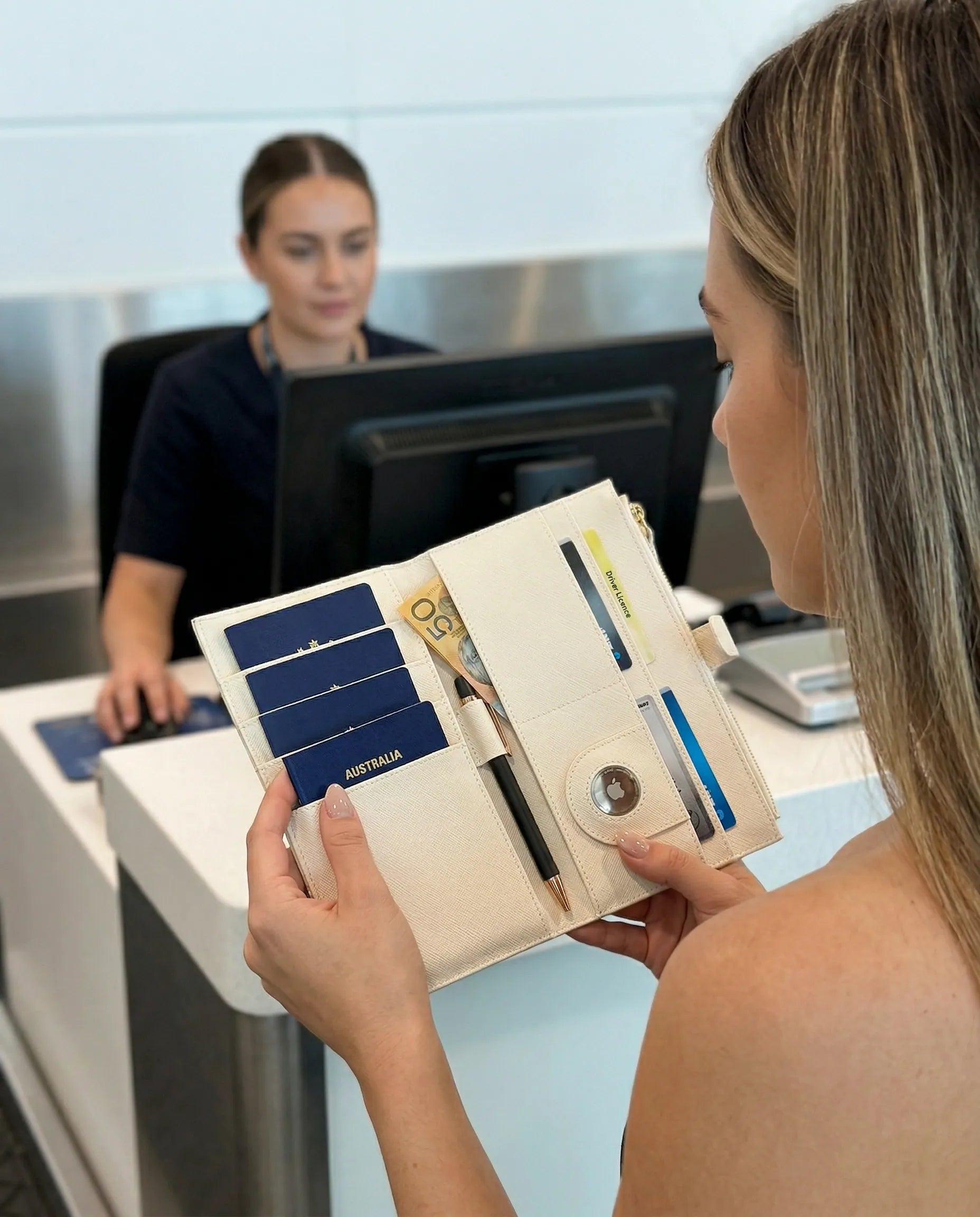 A woman using a Personalised Family Travel Wallet at an airport check-in counter, keeping essentials organized.